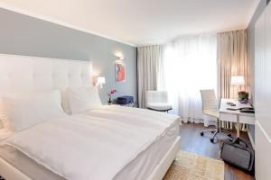 维也纳维也纳拉斐尔美居酒店的白色的卧室配有一张白色的大床和一张书桌