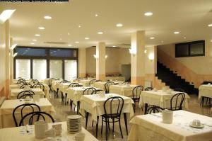 瓦拉泽Hotel Ideale的一间设有白色桌椅的用餐室和楼梯