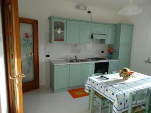 贡内萨Appartamento La Collinetta的厨房配有绿色橱柜和桌椅