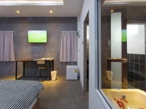 素叻88精品宾馆@素叻他尼机场的带浴缸的浴室和墙上的电视