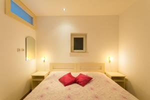 杜布罗夫尼克玛格丽提科公寓的一间卧室配有一张带两个红色枕头的床