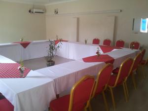 GuluDich Comfort Hotel - Main Branch的一间设有白色桌椅和红色座椅的房间