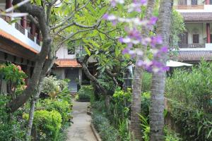 库塔巴昆沙丽度假Spa酒店的穿过种有树木和鲜花的花园的步道