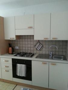 梅扎诺Casa Simion的厨房配有白色橱柜、炉灶和水槽。