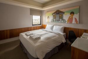 花莲市回然慢时旅居的酒店客房设有一张大床,墙上挂有绘画作品