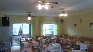 里米尼玛格达酒店的用餐室配有桌椅和吊扇