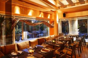 雅典塞奥克塞尼亚酒店的餐厅设有桌椅和大窗户。