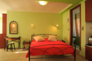 AvgonymaTo Asteri的一间卧室配有红色的床和一张桌子