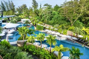 卡伦海滩Holiday Inn Resort Phuket Karon Beach, an IHG Hotel的享有带遮阳伞和棕榈树的度假村游泳池的空中景致