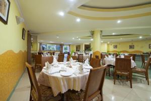 MbaleMbale Resort Hotel的餐厅配有桌椅和白色桌布