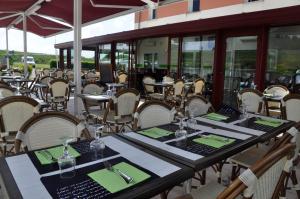 拉苏特兰The Originals City, Hôtel Alexia, La Souterraine (Inter-Hotel)的餐厅配有桌椅和绿色餐巾