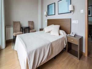 孔门波尔多托瑞斯珂奥斯莫公寓酒店的一间卧室配有一张床和一张桌子及电话