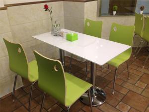 天津青皮树天津市南开区五金城芥园西道酒店的客房内的白色桌子和绿色椅子
