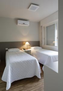 阿雷格里港Apart Hotel Garibaldi的一间卧室设有两张带白色床单的床和窗户。