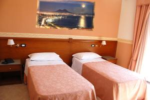Calvizzano多纳托餐厅酒店的酒店客房设有两张床,墙上挂有绘画作品