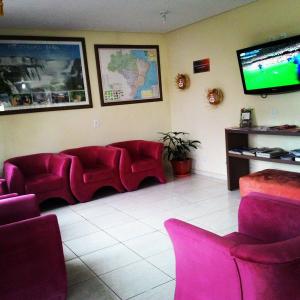 伊瓜苏沙兰迪酒店的一间设有红色椅子和平面电视的等候室