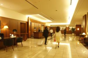 埼玉市Royal Pines Hotel Urawa的几个人穿过大厅