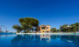 沃尔沃罗Mediterraneo Luxury Suites Halkidiki的一个带椅子的游泳池和一个背景房子