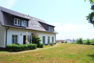 克洛斯特Ferienwohnung Hiddensee Hitthim的前面有草地的白色房子
