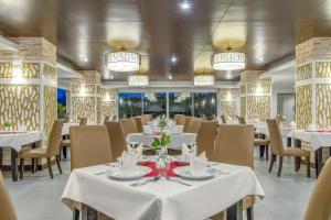 卡伦海滩Chanalai Hillside Resort, Karon Beach的餐厅设有白色的桌椅和吊灯。