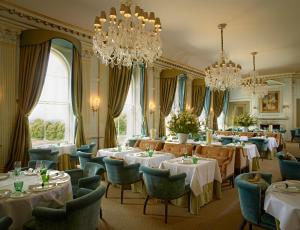 塔普洛Cliveden House - an Iconic Luxury Hotel的用餐室配有桌椅和吊灯。