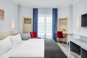 汉堡汉堡阿尔托纳城际酒店的酒店客房,配有一张床和两张红色椅子
