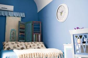 圣塞韦罗B&B Via Roma的一间拥有蓝色墙壁的卧室和墙上的时钟