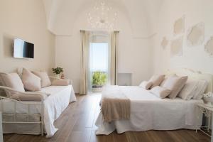 奥斯图尼Biancadamare的一间白色卧室,配有两张床和吊灯