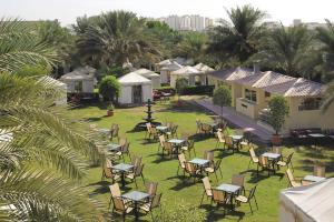 科威特Mövenpick Hotel Kuwait的棕榈树庭院里的一组桌椅