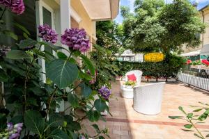 里米尼奥费莉亚卡尔公寓式酒店的庭院里种有紫色花卉,配有白色椅子