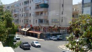 拉纳卡Destalo Court Larnaca Apartment的一条城市街道,汽车停在大楼前
