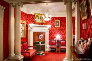 魁北克市皮埃尔别墅酒店的红色的客厅设有红色椅子和壁炉