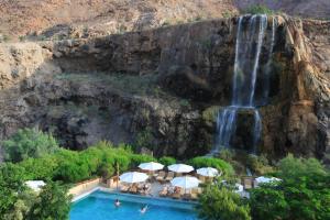 索瓦马迈因温泉酒店的瀑布前的瀑布和游泳池及遮阳伞