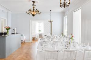 谢莱夫特奥Stiftsgården Konferens & Hotell的一间设有白色桌子、白色椅子和吊灯的房间