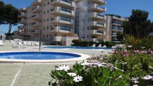 萨洛Apartamento Cap de Salou的一座带游泳池和鲜花的大型公寓大楼
