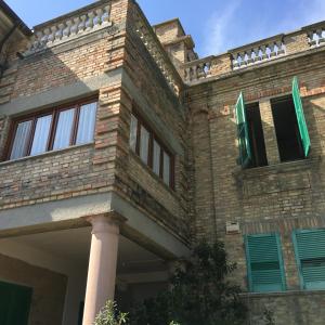 托尔托雷托Appartamento Esmeralda的砖砌建筑,设有绿色窗户和柱子
