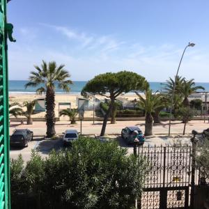 托尔托雷托Appartamento Esmeralda的停车场有汽车和棕榈树,海滩