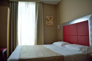 米兰苏萨酒店的一间卧室设有一张大床、红色床头板和窗户