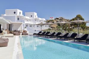 米克诺斯城Livin Mykonos Hotel的毗邻度假酒店的带椅子和遮阳伞的游泳池