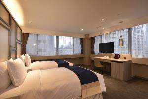 台北洛碁大饭店忠孝馆的酒店客房设有两张床、一张桌子和一台电视。