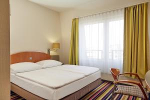 许尔特胡尔特 - 科隆华美达大酒店的一间卧室设有一张床和一个大窗户