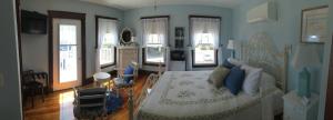 旧奥查德比奇利百加住宿加早餐旅馆的一间卧室设有一张大床,拥有蓝色的墙壁和窗户。