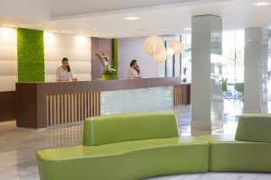 阿尔库迪亚港JS阿尔库迪亚阳光酒店的一个带绿色沙发的大堂和2人