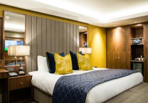 雷阿马斯顿经典英国马斯顿酒店的一间卧室配有一张大床,提供黄色和蓝色的枕头