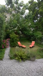 波尔多MAISON D'HÔTES "Bordeaux Wine Lodge"的两把橙色椅子坐在鲜花盛开的花园中