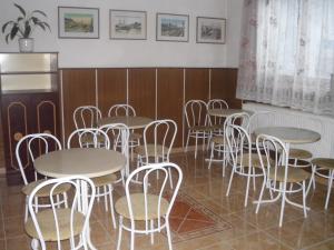 德布勒森潘基欧站酒店的用餐室配有桌子和白色椅子