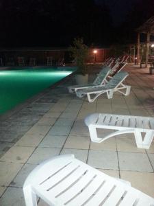 Licciana NardiResidence Le Fontane的夜间游泳池旁的一排白色长椅