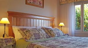 圣卡洛斯-德巴里洛切El Nautico Lodge Bariloche的一间卧室配有一张带枕头的床和两盏灯。