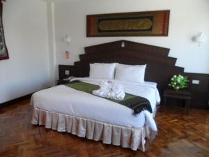 湄宏颂彩虹小木屋酒店的一间卧室配有一张大床,上面有两只猫