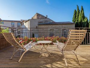 佩兹纳斯Garrigae Distillerie de Pezenas - Hotellerie & Spa的甲板上设有两把椅子和一张桌子,甲板上设有一座建筑